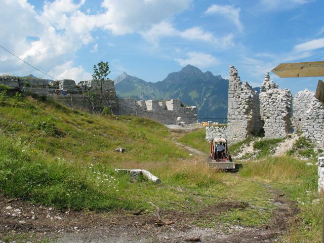 A small bulldozer amidst the Schlokopf ruins.  The wall on the
left is surrounded by scaffolding and workers rebuilding it; the
bulldozer is being used primarily to ferry supplies to the workers.
The barren field through which the bulldozer is driving was a lush
forest only four years ago.