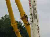 Removing a connecting pin.  Two workers stand on special platforms;
the one on the other side (not visible) drives the pin out with a
sledge while his mate pulls it free.  The crane provides tension so
the whole contraption doesn't collapse suddenly.  You can see, on the
other beam, where the pin has been stored in a special sleeve.