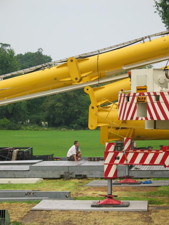 A worker, unconcerned by the tons above him, kneels under the
collapsing support beams.  He is placing a large brick, apparently to
give the hinges something to land on.