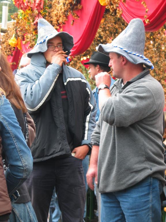 Revelers at Oktoberfest.  I have no proof, but these guys look like American college students to me.  I base the conclusion on the cheap souvenir hats, the general manner of dress, and the way they are smoking cigars as if it's not an accustomed thing.