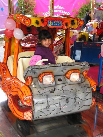 Xandie takes a ride in a Flintstones car at Oktoberfest.