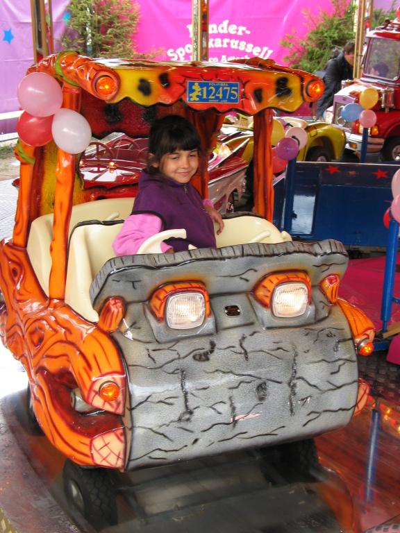 Xandie takes a ride in a Flintstones car at Oktoberfest.