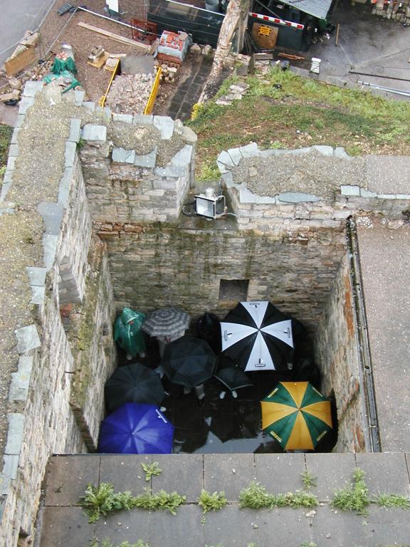 An umbrella-carrying group of tourists gathers around their guide at
Lincoln Castle.  Photo by Pat.