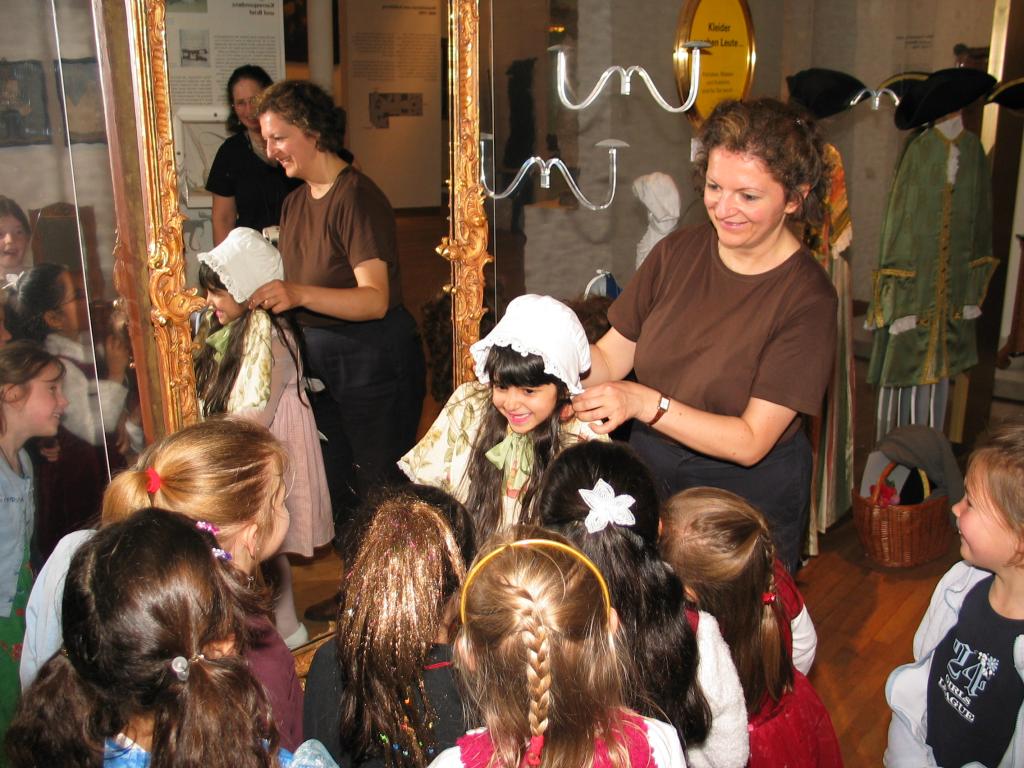 Xandie tries on some old-fashioned clothes during her birthday party while her friends watch.