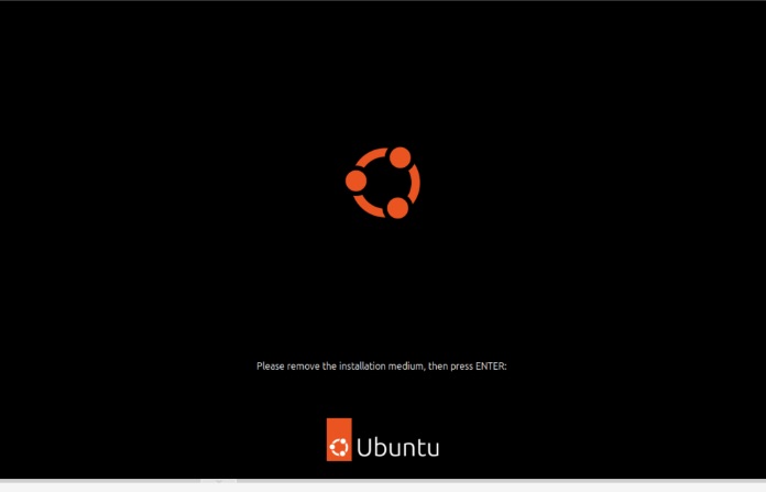 The noVNC console showing a black screen with the Ubuntu logo and the text Please remove the installation medium, then press ENTER